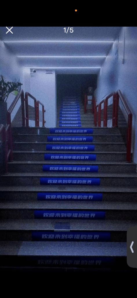 A dim staircase with the Chinese phrase 欢迎来到幸福的世界 repeated on its steps.