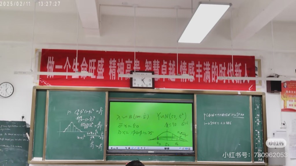 A Chinese classroom with a red motivational slogan above the blackboard.